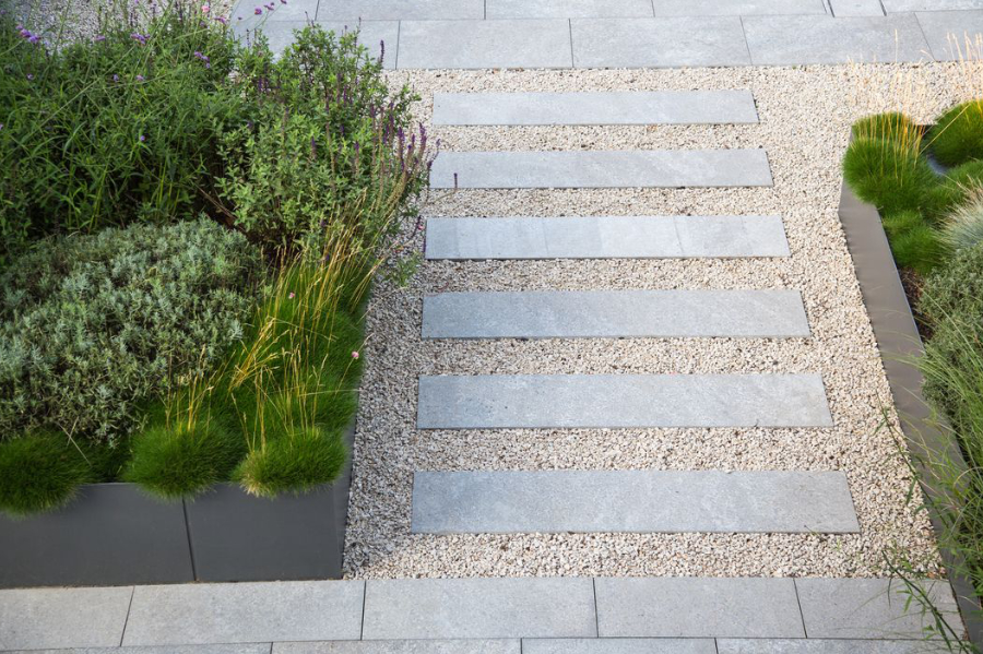 Terrassenplatten aus Naturstein zu einem Übergangsweg verlegt